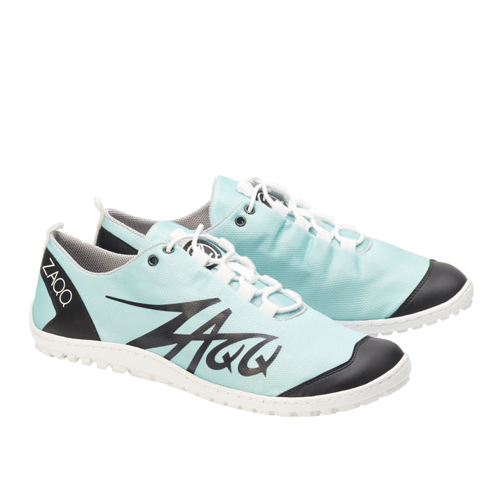 Ein Paar SQIM Turquoise Sportschuhe von ZAQQ, in türkisem Design mit schwarzen Akzenten, hergestellt aus veganem Recycling-Gewebe. Diese nachhaltigen Barfußschuhe zeigen den ZAQQ-Text an der Seite und an der Ferse und sind mit weißen Schnürsenkeln und strukturierten weißen Sohlen ausgestattet, wodurch umweltfreundliche Materialien nahtlos mit einem sportlichen Stil verbunden werden.