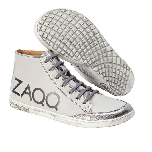 Wir präsentieren den SQYLA Grey von ZAQQ, ein Paar High-Top-Sneaker aus Nappaleder. Diese stylischen Schuhe haben graue Schnürsenkel, eine auffällige silberne Zehenkappe und das auffällige ZAQQ-Logo der Marke an der Seite. Sie sind mit einer Kautschuksohle für hervorragenden Halt ausgestattet und verfügen über eine weiße Basis, ergänzt durch metallische Akzente für ein elegantes und modernes Erscheinungsbild.