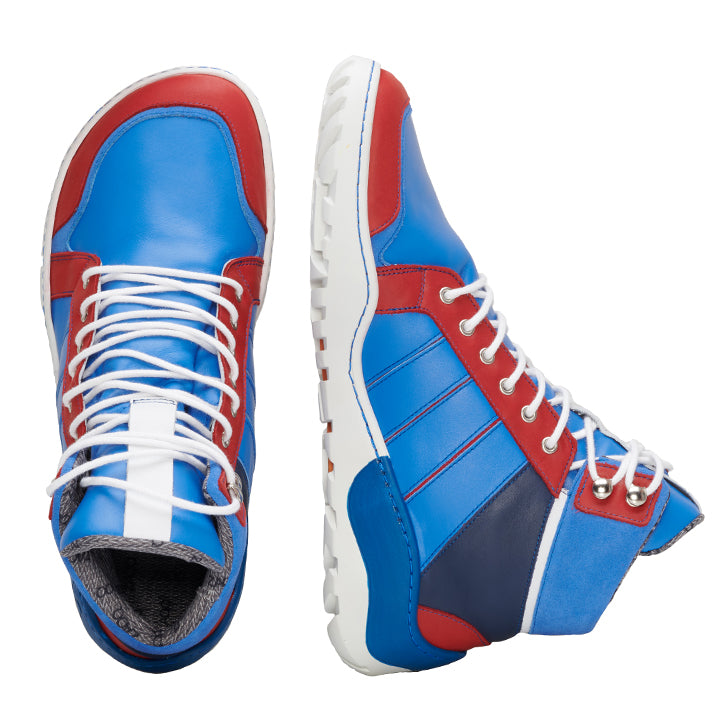 Die Q2 Blue Waterproof Sneaker von ZAQQ sind in einem lebhaften Mix aus blauen, roten und weißen Einsätzen mit weißen Schnürsenkeln gehalten und zeichnen sich durch ein sportliches High-Top-Design aus. Ihr schlichtes Erscheinungsbild fällt vor einem schlichten weißen Hintergrund auf.