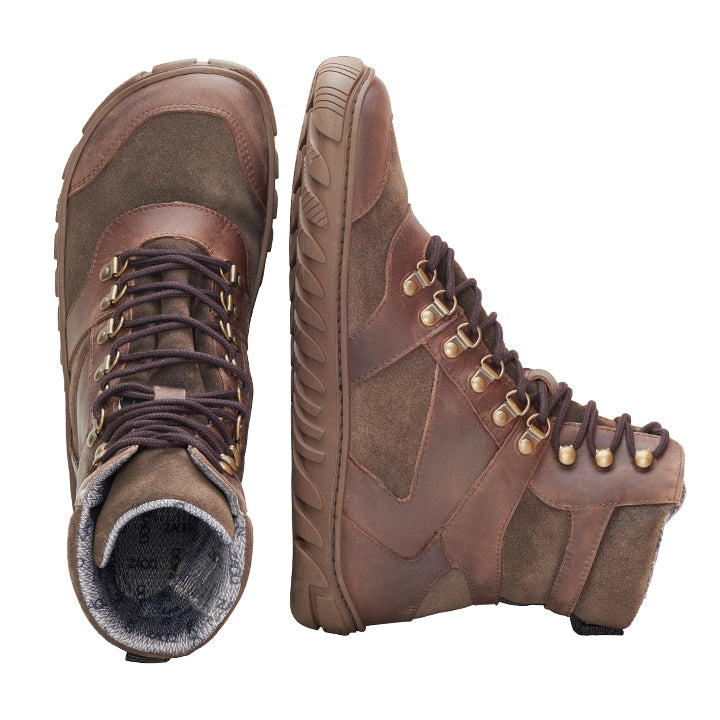 Die wasserdichten Wanderstiefel EXPLORER Brown von ZAQQ zeichnen sich durch eine Kombination aus Leder- und Wildledertexturen aus, die für Stil und Haltbarkeit sorgen. Mit robusten Sohlen und dunkelbraunen Schnürsenkeln steht der linke Stiefel aufrecht, während der rechte Stiefel auf der Seite liegt und sowohl die Draufsicht als auch die Seitenansicht zeigt.