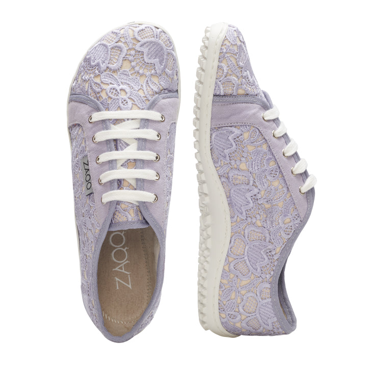 Wir präsentieren die QELLY Purple-Sneaker von ZAQQ, eine perfekte Wahl für Sneaker Damen. Diese hellvioletten Schnürsneaker verfügen über aufwendige Blumenspitzen- und Blumenstickerei-Details, ergänzt durch weiße Schnürsenkel und Sohlen. Ein Schuh ist elegant von der Seite zu sehen, während der andere von oben betrachtet wird.