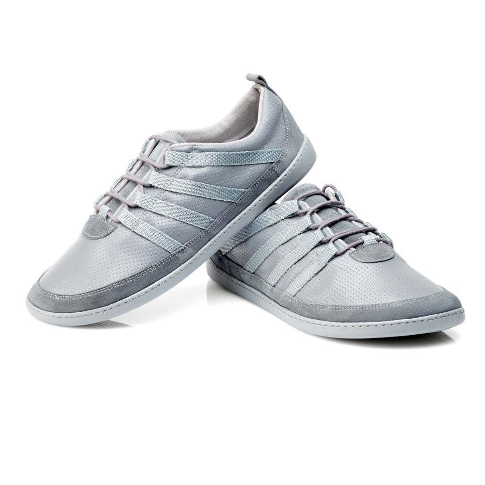 Die SPARQ Low Grey Sneaker von ZAQQ sind elegant aus Nappaleder in hellgrau gefertigt. Sie zeichnen sich durch ein schlichtes Design mit mehreren dekorativen Riemen und weißen Sohlen aus. Schräg positioniert, wird ein Schuh stilvoll nebeneinander präsentiert.