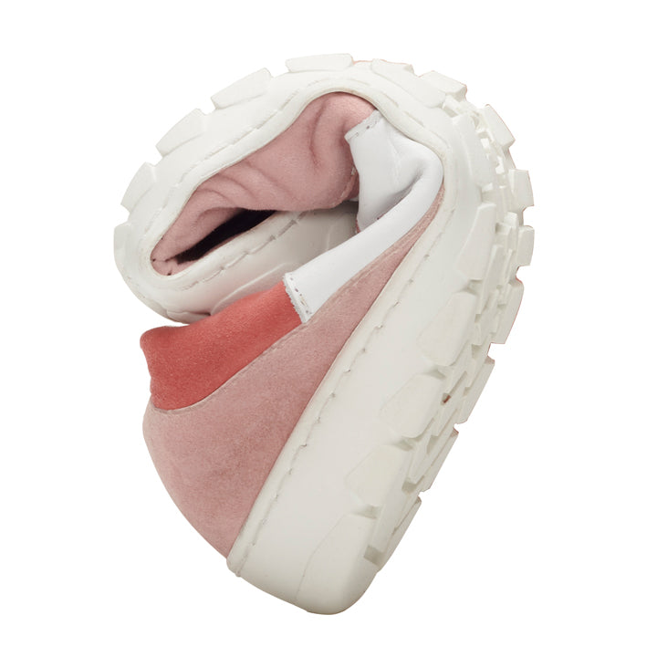 Der QARTER Rosa Sneaker von ZAQQ in Pink und Weiß wird in der Mitte gebogen präsentiert, um seine Flexibilität hervorzuheben. Er verfügt über eine dicke, strukturierte Sohle und ein Obermaterial aus weichem Premium Nappa- und Veloursleder.