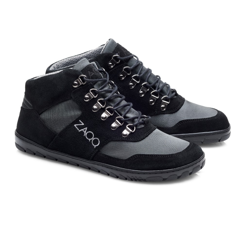 Die HIQE Mid Black Waterproof Wanderschuhe sind mit Metallösen und schwarzen Schnürsenkeln ausgestattet und tragen den Markennamen ZAQQ deutlich sichtbar an der Seite. Als vielseitige Outdoor-Schuhe bieten sie Komfort und Halt auf jedem Terrain.