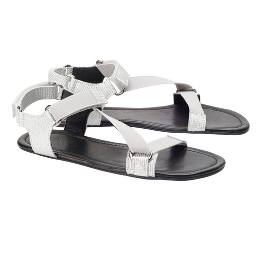 Ein Paar stylische MIQA Silver-Sandalen von ZAQQ mit weißen Riemen und einer flachen Gummisohle. Das Design umfasst Klettverschlüsse und einen Zehenschlaufenriemen für zusätzlichen Halt und Flair.