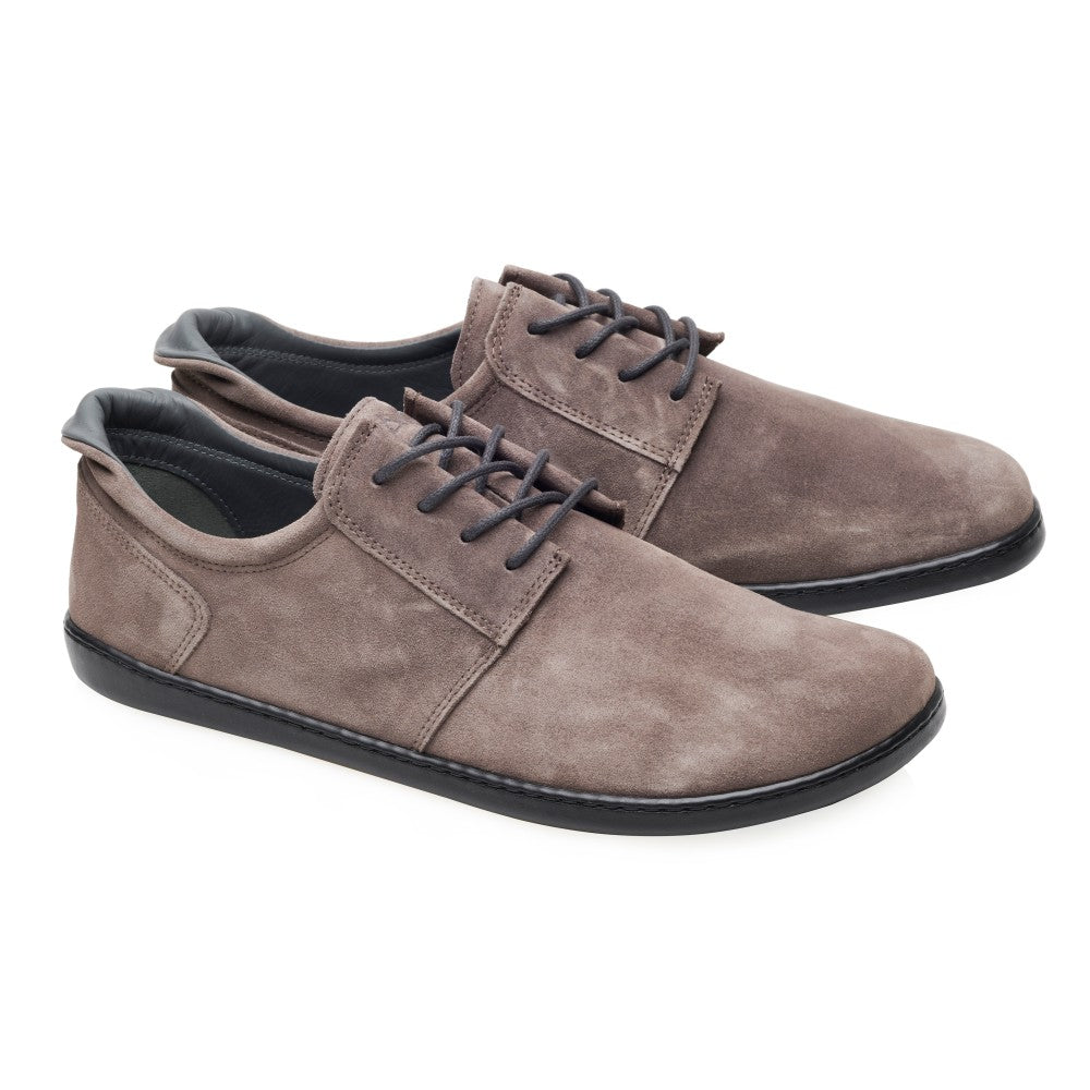 Ein Paar graue Veloursleder-Freizeitschuhe mit schwarzer Sohle und Schnürsenkeln, nebeneinander auf weißem Hintergrund. Diese ZAQQ PIQUANT Sneaker zeichnen sich durch ein Low-Cut-Design mit minimalistischem Stil aus und bieten außergewöhnlichen Tragekomfort für den Alltag.