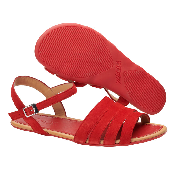 Wir präsentieren die QEIRA Red Sandalen von ZAQQ: Diese Sandalen in leuchtendem Rot sind mit offenen Zehen und eleganten Knöchelriemen aus Veloursleder versehen. Eine Sandale ist stehend abgebildet, während die andere ihre strukturierte Kautschuksohle zeigt. Die silberne Schnalle verleiht eine elegante Note und verbindet Stil mit lässigem Charme.