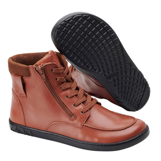 Ausgestellt wird ein Paar ZAQQ ROQA Cognac Leder High-Top-Sneaker mit schwarzer Sohle. Ein Schuh steht aufrecht und verfügt über sichtbare Schnürsenkel und einen seitlichen Reißverschluss, während der andere das strukturierte Sohlenmuster dieses stylischen Schnürboots hervorhebt.