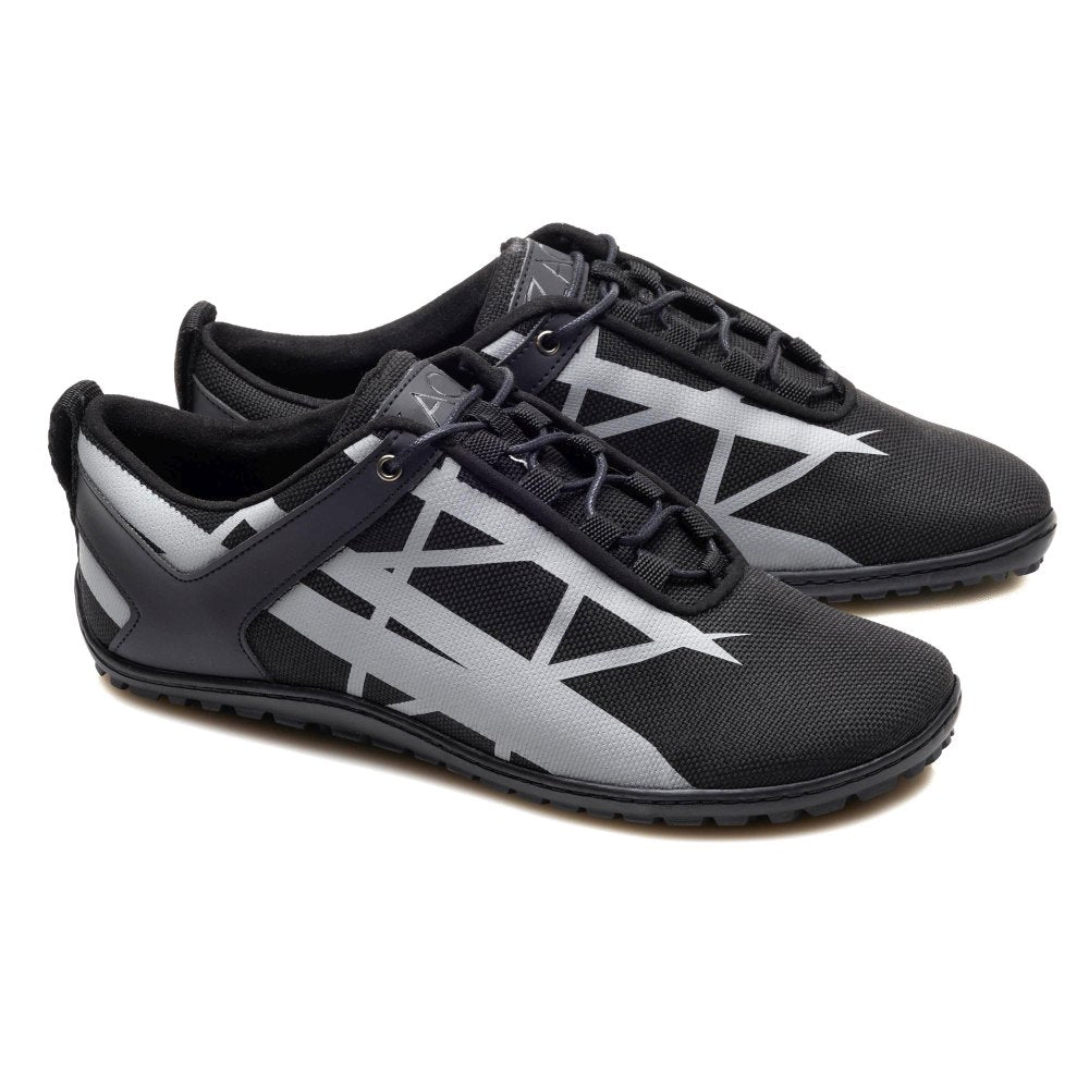 Die XIQOT Black Sportschuhe von ZAQQ präsentieren ein elegantes schwarzes Design mit grauen geometrischen Mustern an den Seiten, ergänzt durch schwarze Schnürsenkel und einen Low-Cut-Stil. Diese Schuhe bestehen aus veganem Meshgewebe und verfügen über eine flexible Kautschuksohle. Mit ihrer strukturierten Sohle bieten sie Haltbarkeit und Halt und eignen sich perfekt für Freizeitausflüge oder sportliche Aktivitäten.