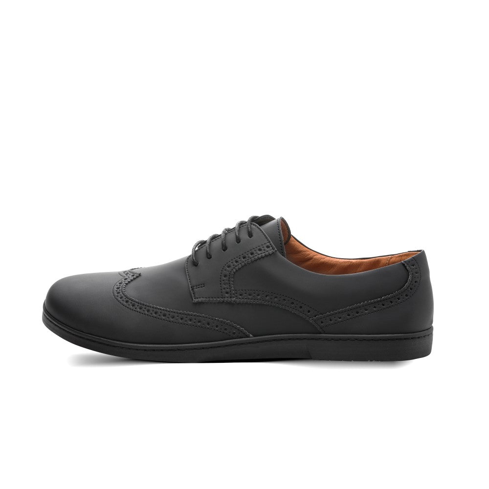 Der Schuh ZAQQ BRIQ Brogue Vegan Black ist ein schwarzer Brogue aus veganem Leder mit aufwendigen Details und Schnürsenkeln, gepaart mit einer rutschfesten Sohle, alles präsentiert vor einem schlichten weißen Hintergrund.