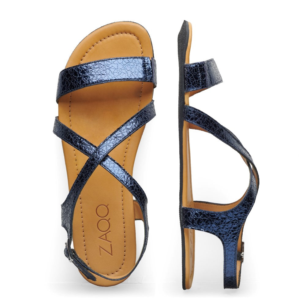 Die QEE-Blue Sandalen von ZAQQ haben stilvolle schwarze, strukturierte, überkreuzte Riemen und ein hellbraunes Fußbett. Die Seitenansicht zeigt eine schmale Sohle und einen Knöchelriemen mit Schnalle aus hochwertigem Nappaleder. Das Markenlogo von ZAQQ ist elegant auf dem Fußbett angebracht.