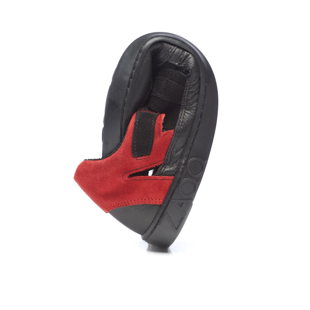 Der Slipper QERRY Black Red von ZAQQ beweist seine Flexibilität durch eine Biegung und präsentiert sein Obermaterial aus Veloursleder und die Gummisohle, was ihn ideal für Outdoor-Abenteuer macht.