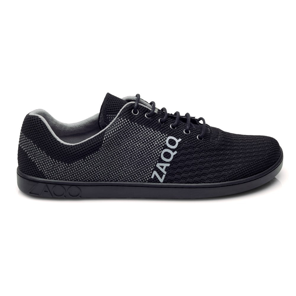 Wir präsentieren den QNIT Black von ZAQQ: einen schwarz-grauen Sportschuh mit strukturiertem Design, auf dessen Seite der Markenname ZAQQ deutlich zu sehen ist. Dieser vegane Strickschuh bietet ein flaches Design mit Schnürsenkeln und einer dunklen Sohle. Er ist aus atmungsaktivem Baumwollgewebe gefertigt, um optimalen Komfort zu gewährleisten.