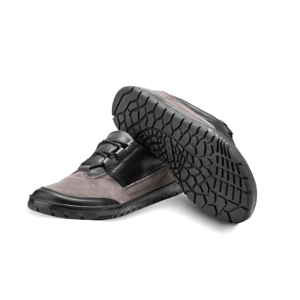 Wir präsentieren die wasserdichten Schuhe QUEST Low Black von ZAQQ. Diese stilvollen Lederschuhe bestechen durch eine Mischung aus schwarzen und grauen Einsätzen, ergänzt durch Gummisohlen. Ausgestattet mit einem robusten Profildesign bieten sie hervorragende Traktion und Haltbarkeit. Ein Schuh wird aufrecht präsentiert, während der andere so positioniert ist, dass die Sohle hervorgehoben wird.