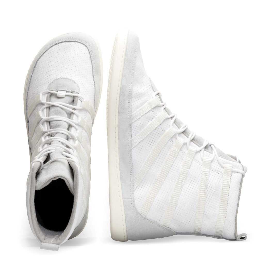 Wir präsentieren den SPARQ High White von ZAQQ: Ein Paar High-Top-Sneaker in makellosem Weiß, sorgfältig gefertigt aus hochwertigem Nappaleder, mit aufwendigen Lochmustern. Ein Schuh steht vertikal und zeigt seine cremefarbene, strukturierte Sohle, die seine Rutschfestigkeit betont. Der andere Schuh liegt flach und zeigt seine robusten Schnürsenkel und die Zunge.